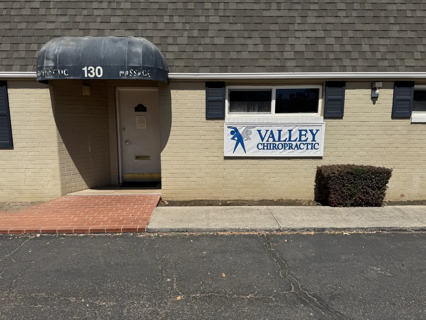 Entrance to the Valley Chiropractic Manteca office at suite 130, with the practice sign on the brick exterior and parking right at the door