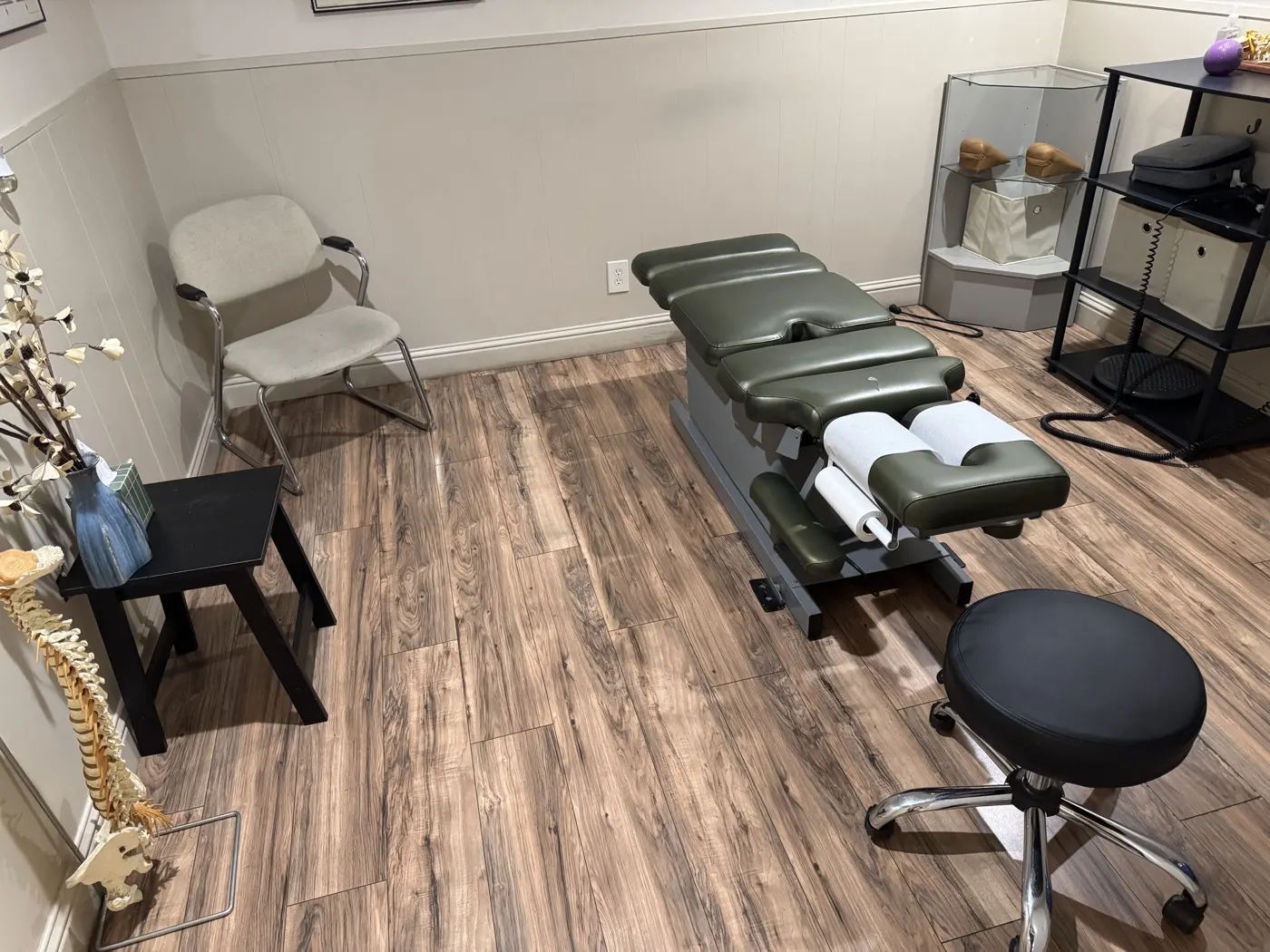 Second adjustment room at the Manteca office with a green chiropractic table, spine model, and orthotics display