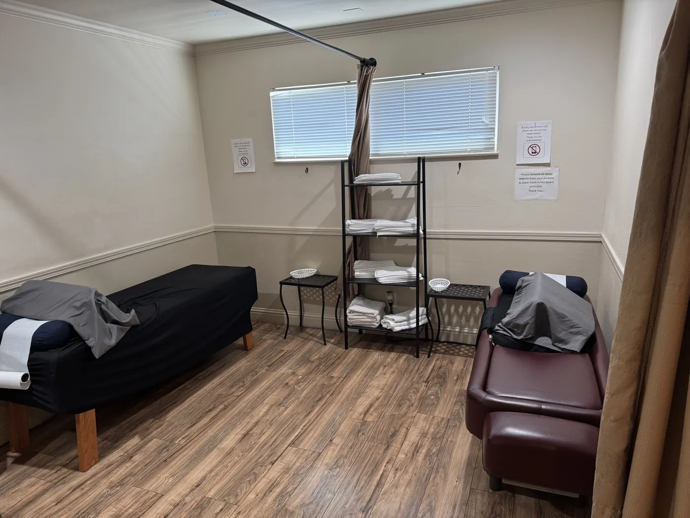 Therapy room at the Manteca office with treatment tables, fresh linens on open shelving, and a privacy curtain