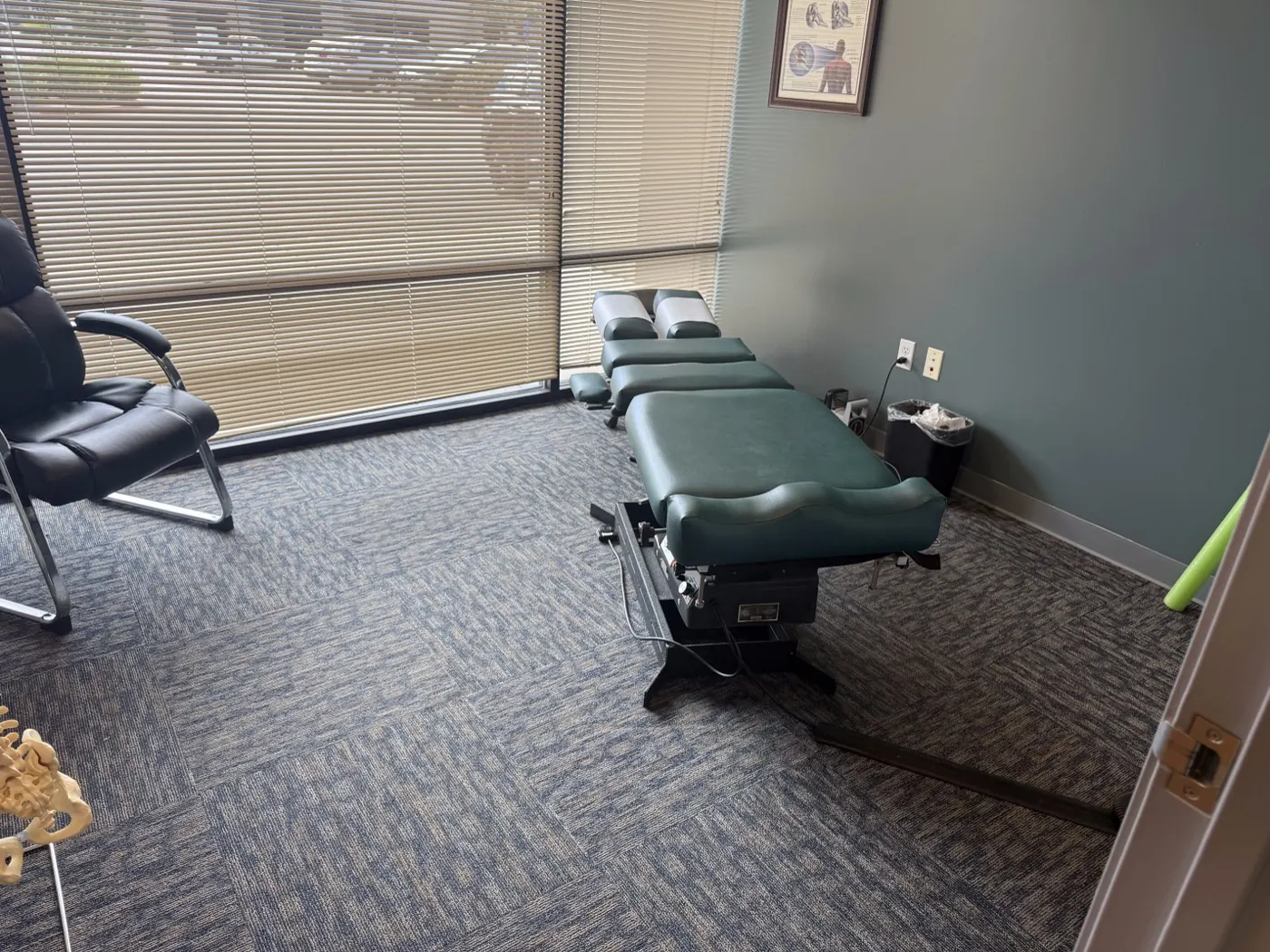 Private adjustment room at the Ripon office with a green chiropractic drop table and window blinds