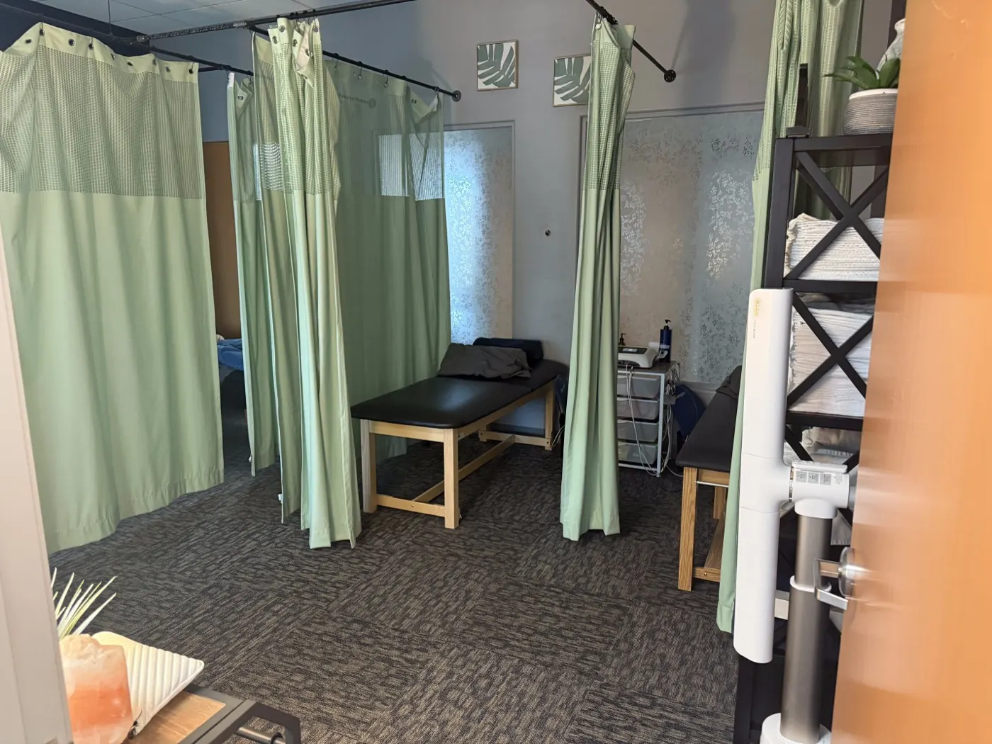 Curtained therapy bays at the Ripon office with treatment tables and electrical stimulation equipment