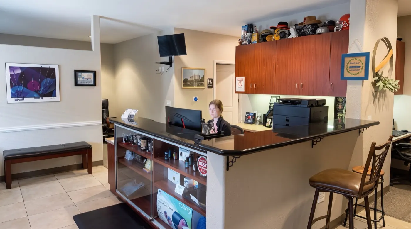 Front desk and reception area at the Tracy chiropractic office with a staff member at the counter
