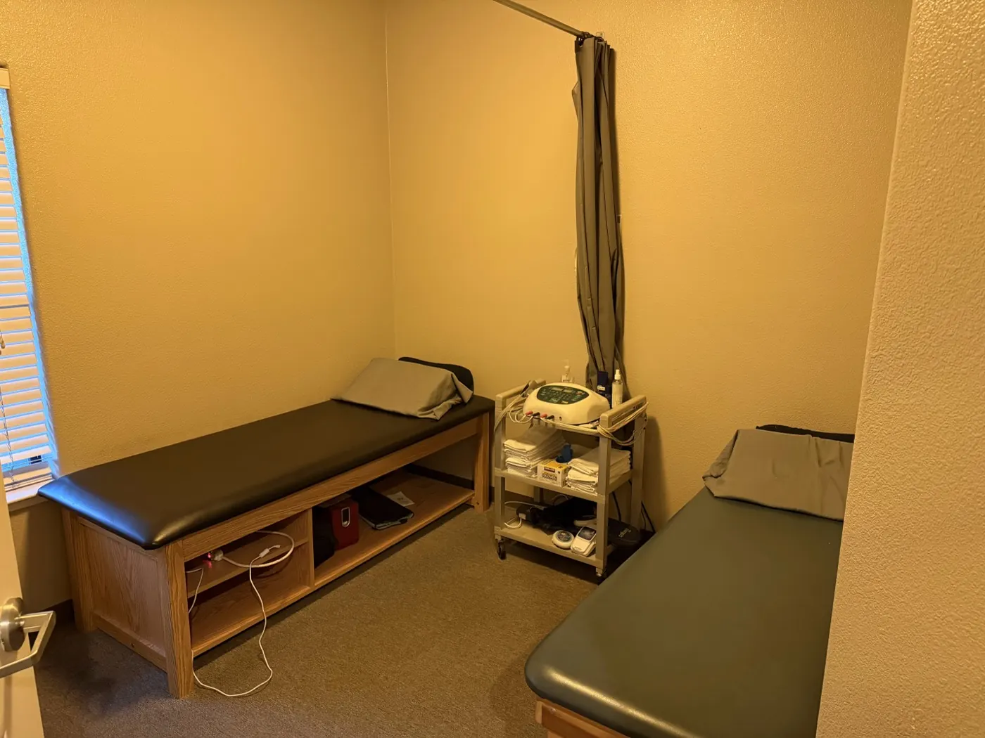Therapy room at the Tracy office with treatment tables and an electrical stimulation unit on a rolling cart